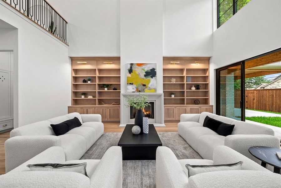 The living room features high ceilings, hardwood flooring, and a fireplace with a light-colored mantel