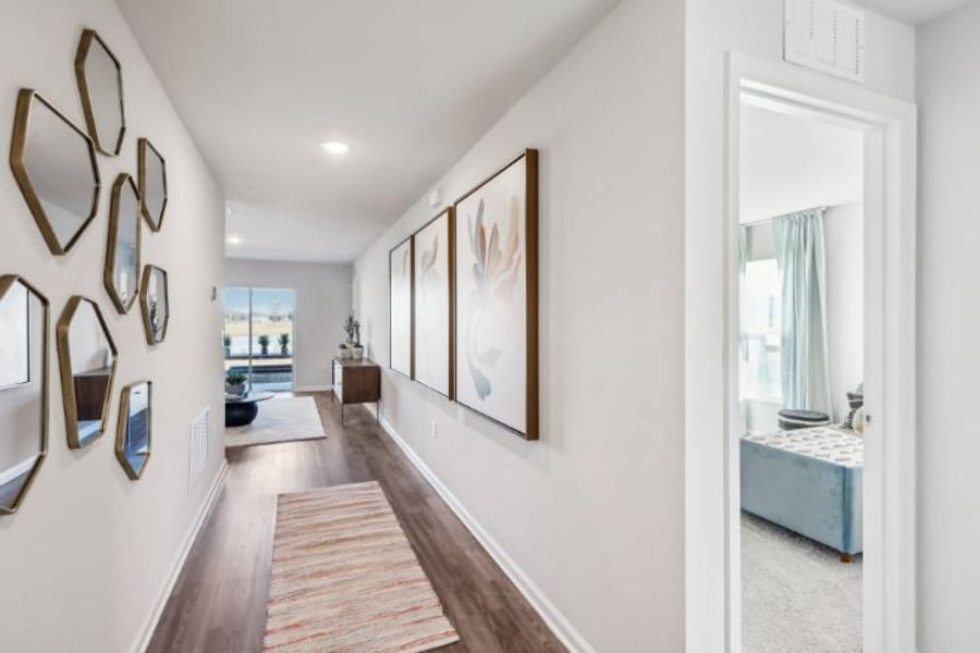 A hallway with a rug and a mirror.