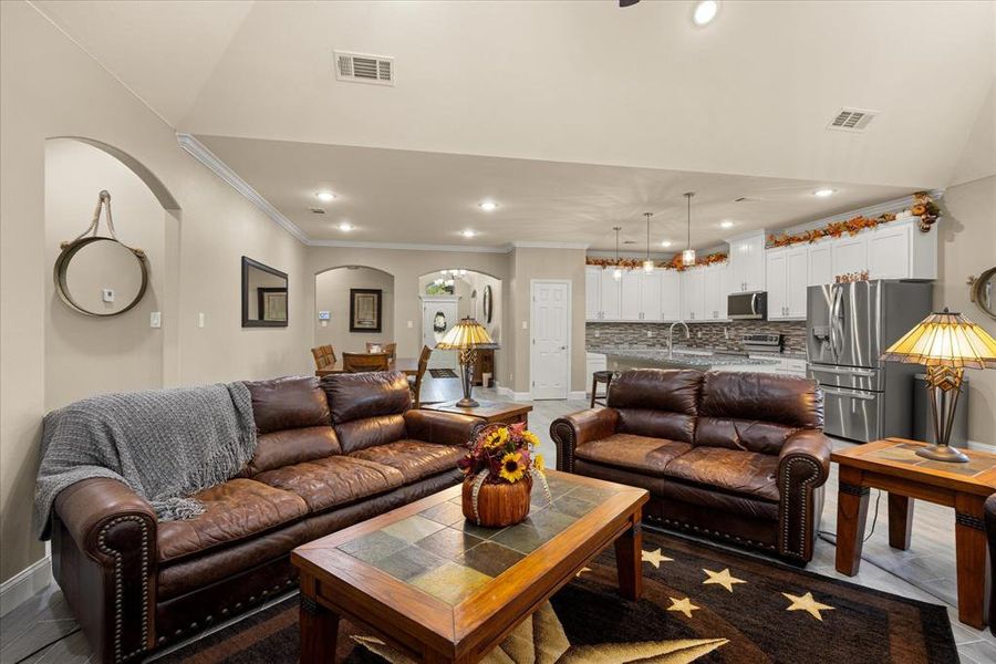 Living room featuring ornamental molding, arched walkways, recessed lighting, and a chandelier Living room featuring ornamental molding, arched walkways, recessed lighting, and a chandelier