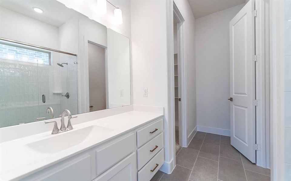 Bathroom featuring a white vanity with an integrated sink, brushed nickel faucet, large mirror, and overhead linear vanity light fixture