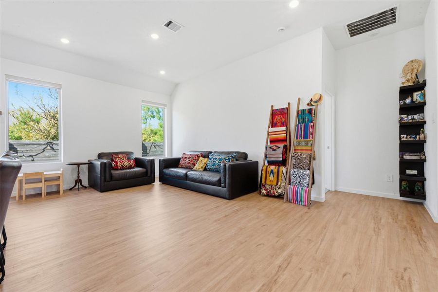 Bright and spacious living area with large windows, modern LVP flooring, and contemporary furnishings.