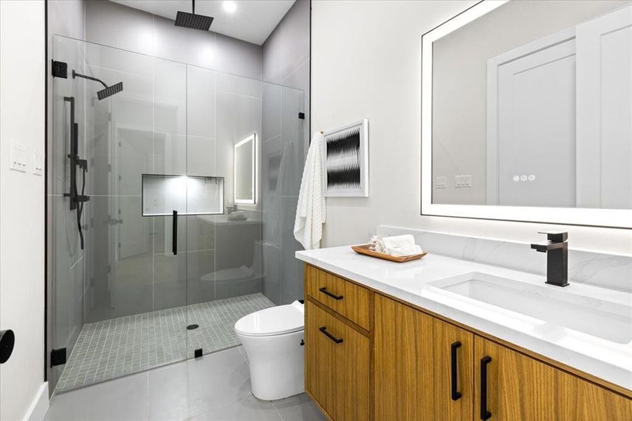 Bathroom with a shower with shower door, vanity, tile patterned floors, and toilet