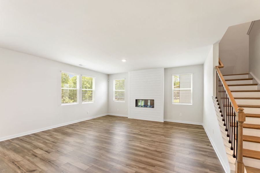 A large empty room with a wood floor and a staircase. A large empty room with a wood floor and a staircase.