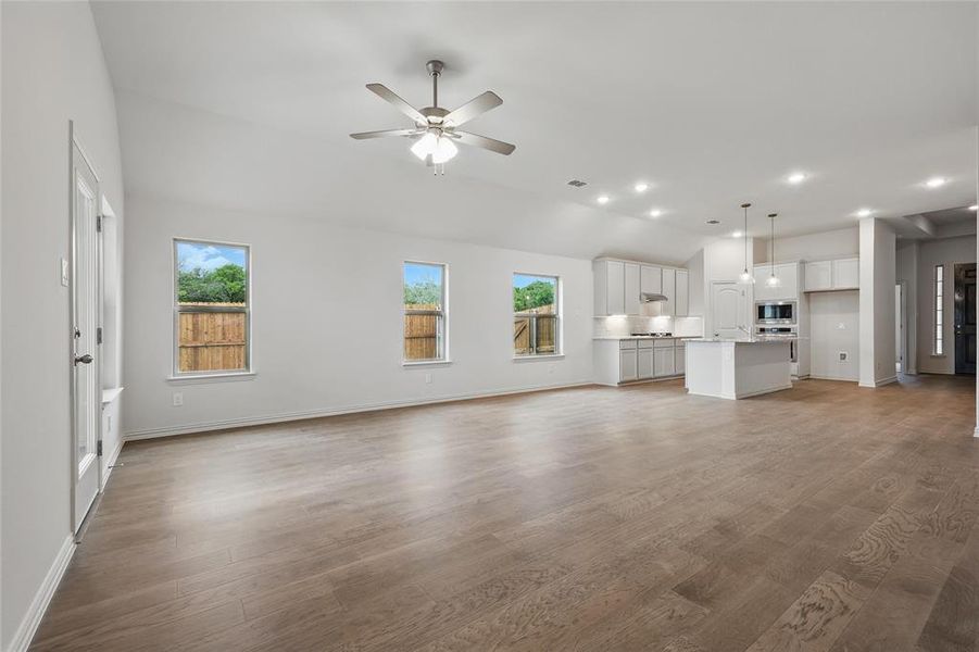 Unfurnished living room featuring dark wood-style flooring, ceiling fan, recessed lighting, and lofted ceiling