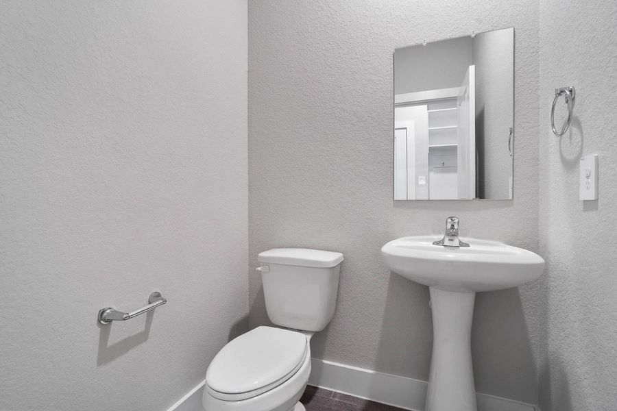 A perfectly positioned guest half-bath on the main level, featuring a crisp white pedestal sink and toilet, ideal for visitors. A perfectly positioned guest half-bath on the main level, featuring a crisp white pedestal sink and toilet, ideal for visitors.