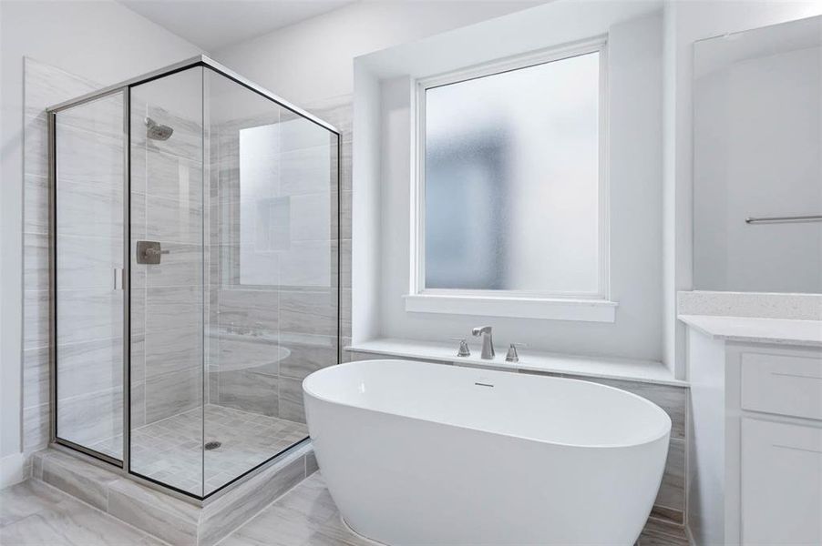Primary bathroom featuring a soaking tub, separate walk-in shower, and bright neutral finishes.