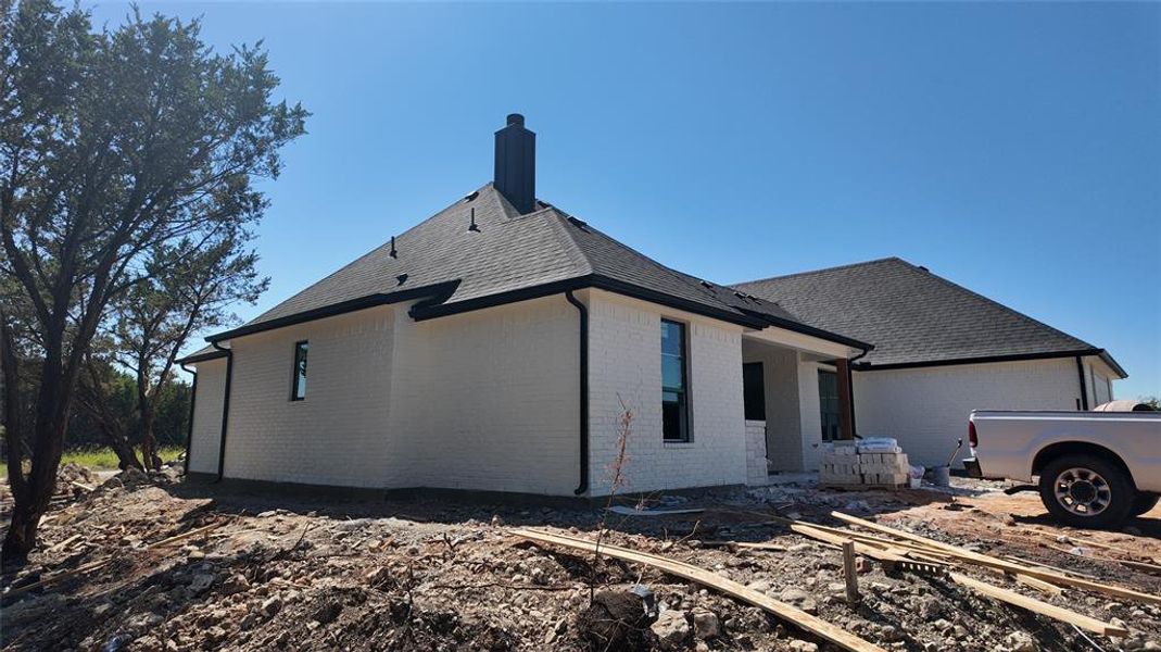 View of side of home featuring roof with shingles, brick siding, and a chimney View of side of home featuring roof with shingles, brick siding, and a chimney