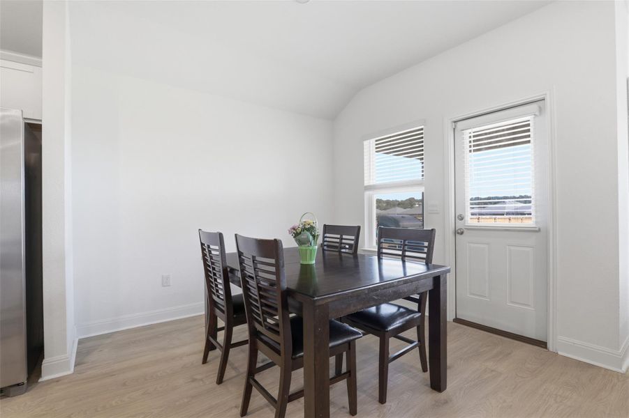 Bright dining area featuring wood-finish flooring and a white exterior door