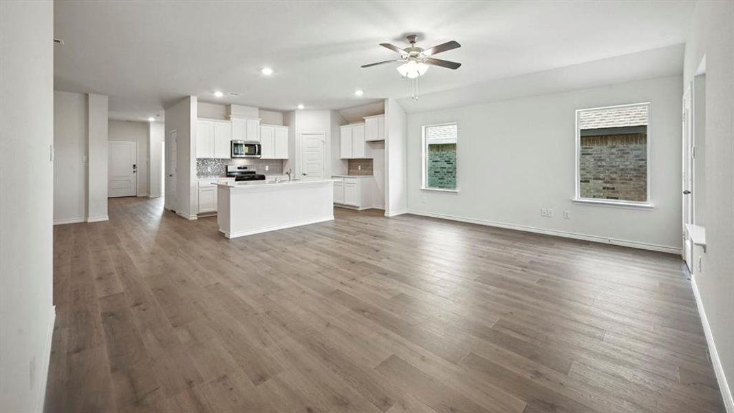 Open-concept living area featuring wood-finish flooring, recessed lighting, and a ceiling fan Open-concept living area featuring wood-finish flooring, recessed lighting, and a ceiling fan