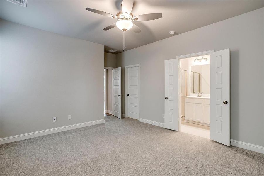 Unfurnished bedroom with connected bathroom, light colored carpet, sink, and ceiling fan