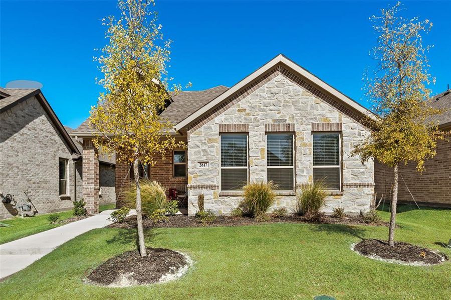View of front of home featuring stone siding, a front lawn, and brick siding View of front of home featuring stone siding, a front lawn, and brick siding