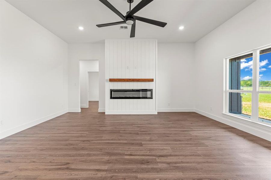 Unfurnished living room with a ceiling fan, wood finished floors, a fireplace, and recessed lighting