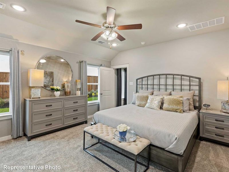 Bedroom featuring ceiling fan, lofted ceiling, light carpet, and multiple windows