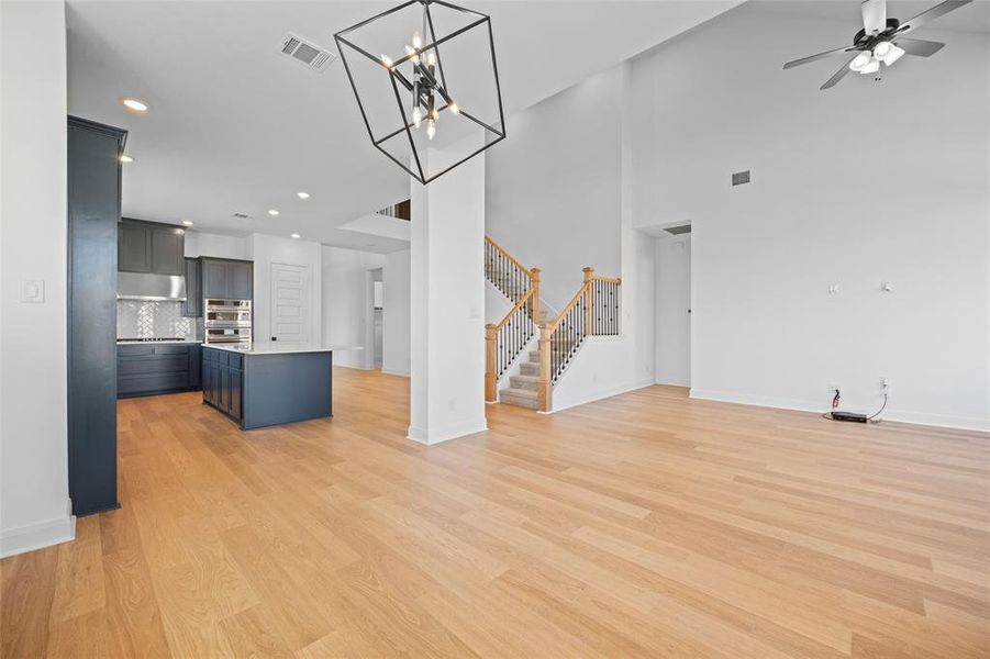 Kitchen featuring backsplash, stainless steel double oven, an island with sink, and light wood-type flooring