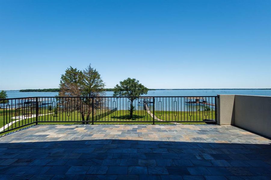 Expansive outdoor terrace featuring multi-toned paver flooring and a black metal railing