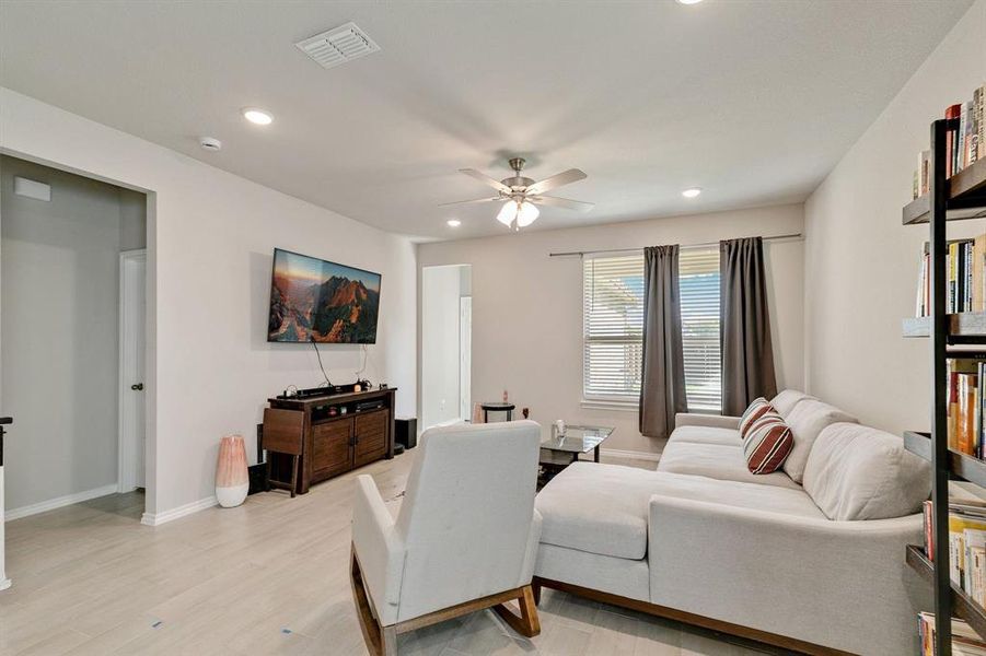 Living room with ceiling fan and light hardwood / wood-style floors