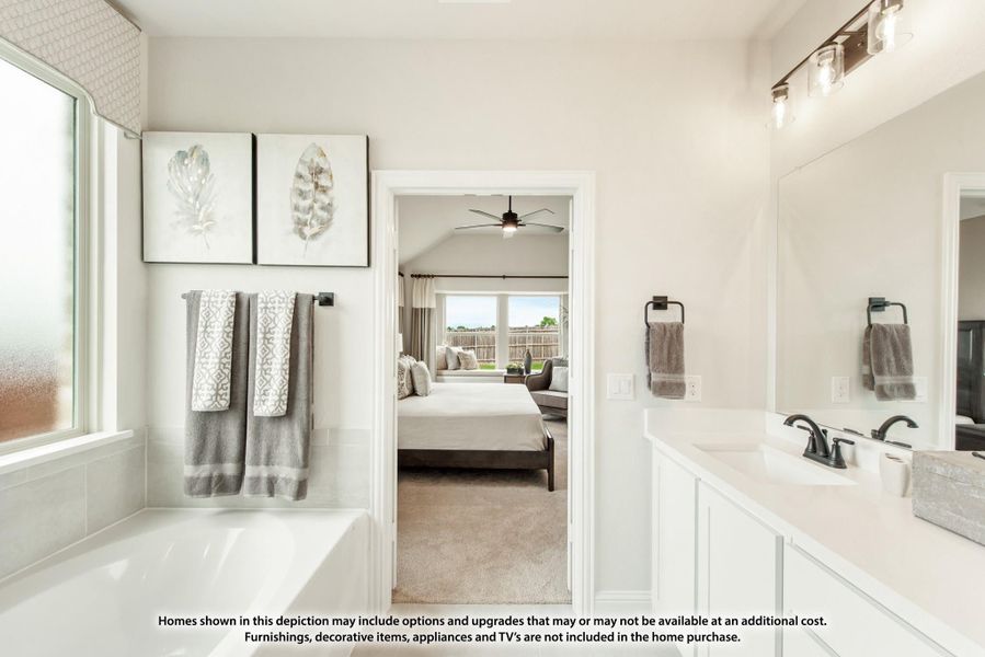 Ensuite bathroom with soaking tub, white vanity, and open doorway to master bedroom with vaulted ceiling