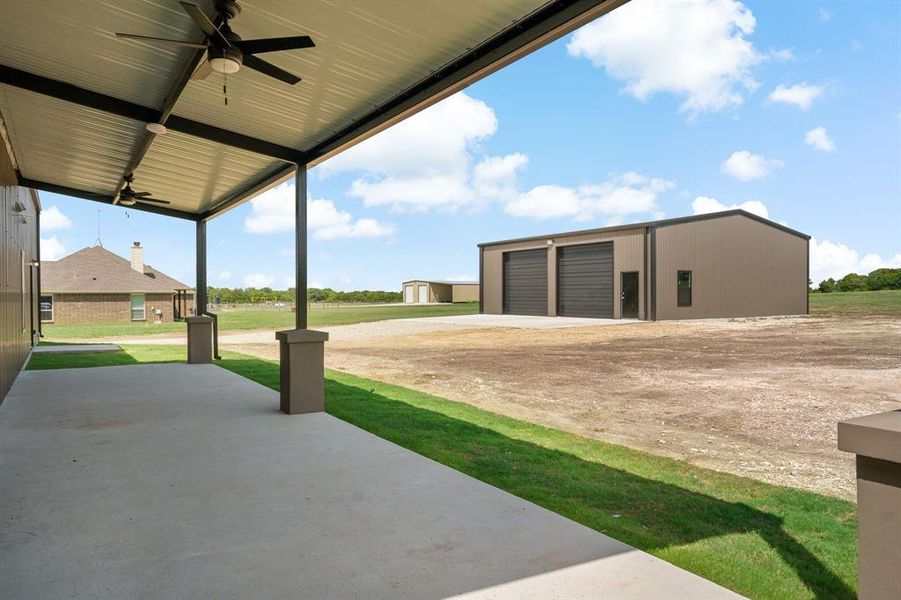 View of yard with a garage, ceiling fan, and an outbuilding