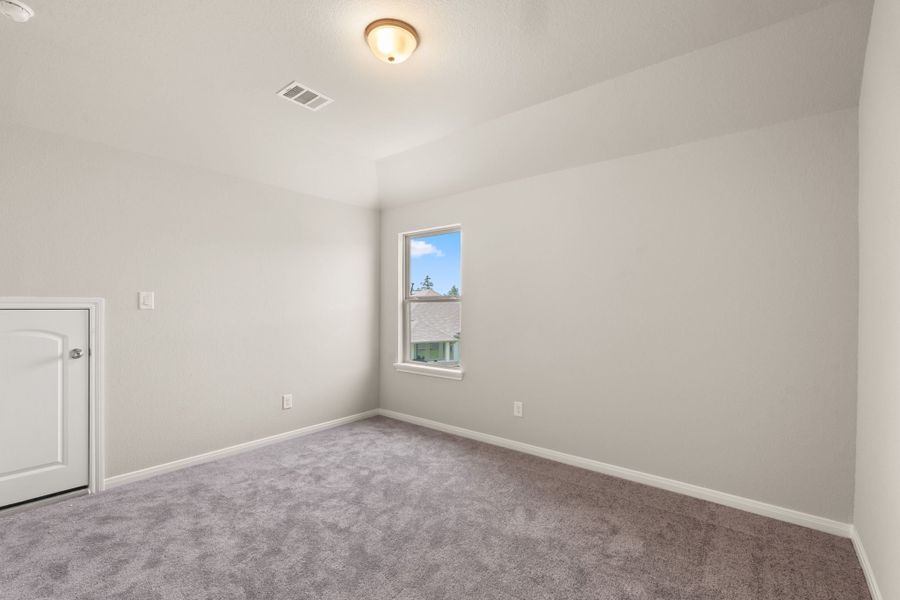 The fourth bedroom features plush carpet, neutral paint and a large window.