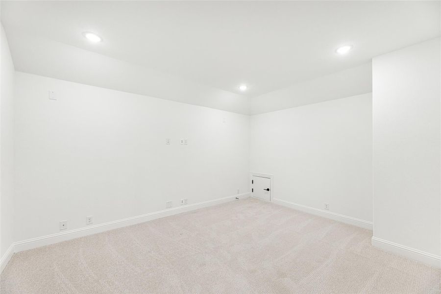 Empty room with white walls, beige carpet, recessed lighting, and a small access door