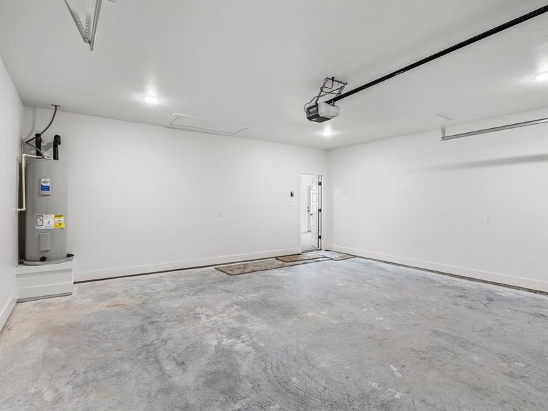 Garage with baseboards, a garage door opener, and water heater