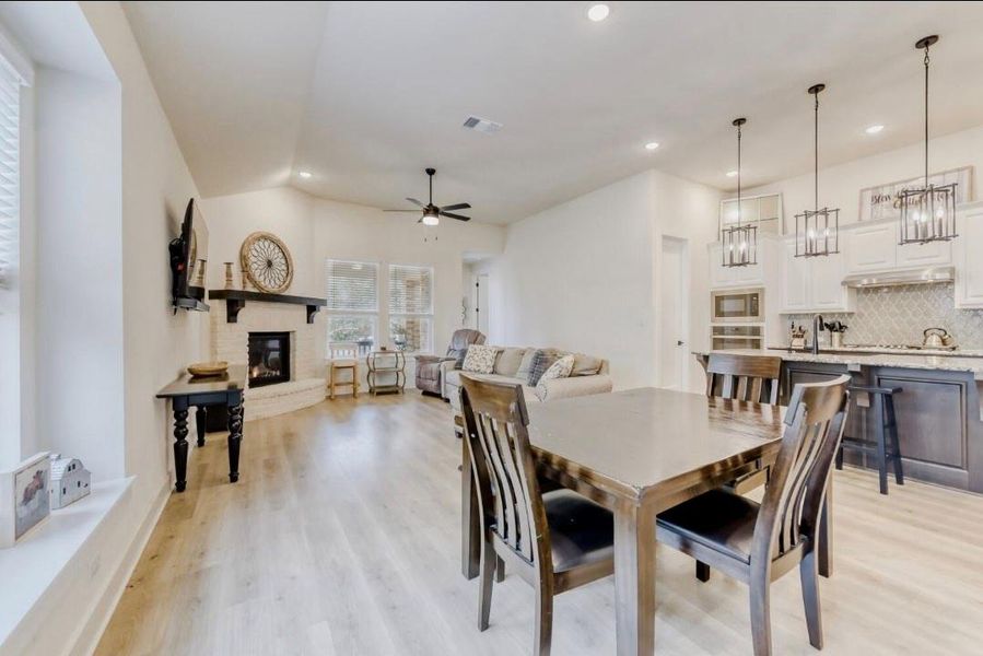 Dining area with recessed lighting, light wood finished floors, a fireplace, a ceiling fan, and lofted ceiling