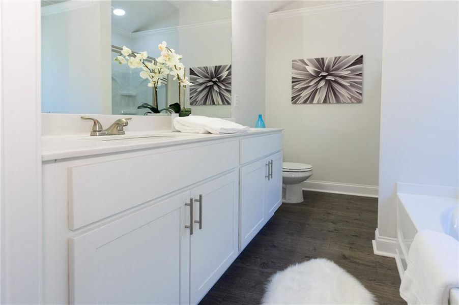 Bathroom featuring toilet, crown molding, a bath, hardwood / wood-style floors, and vanity