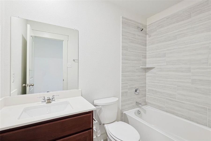 Full bathroom with tiled shower / bath combo, toilet, and vanity