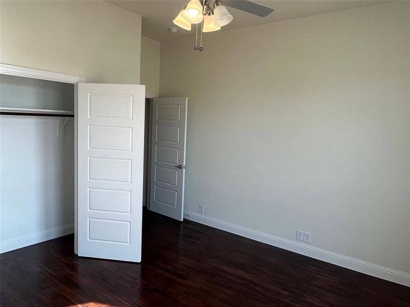 Unfurnished bedroom with a closet, ceiling fan, and dark wood-type flooring