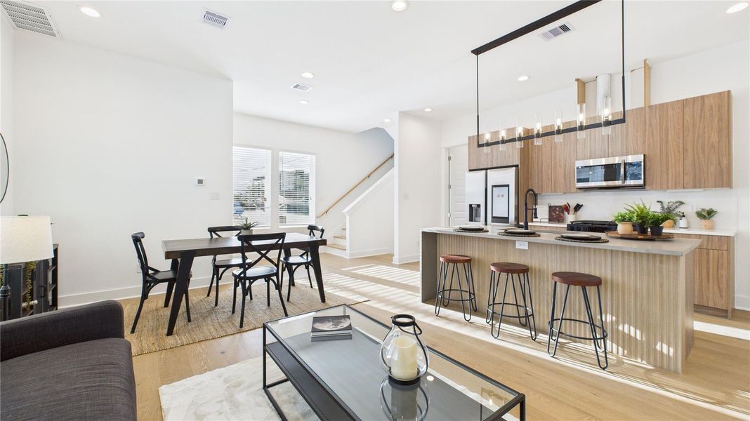 The welcoming second-floor open-concept living area seamlessly combines the living room, dining room, and kitchen, filled with natural light and enhanced by modern finishes and engineered hardwood flooring throughout, creating a bright and inviting space ideal for everyday living and entertaining.