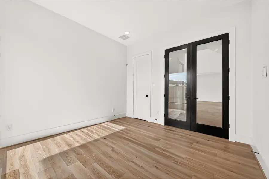 HOME OFFICE: The versatile first-floor home office features modern French doors and a closet, allowing the space to easily function as an additional bedroom if desired.