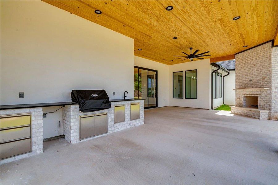 An inviting outdoor living space features an impressive fireplace and a fully equipped outdoor kitchen.