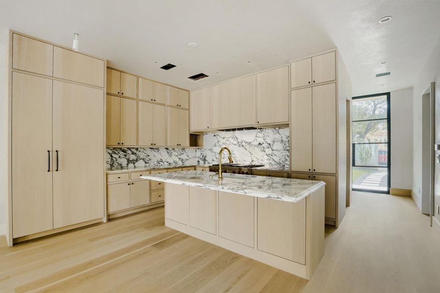 Culinary aspirations meet sophisticated design in this kitchen, featuring seamless cabinetry and a striking marble backsplash.