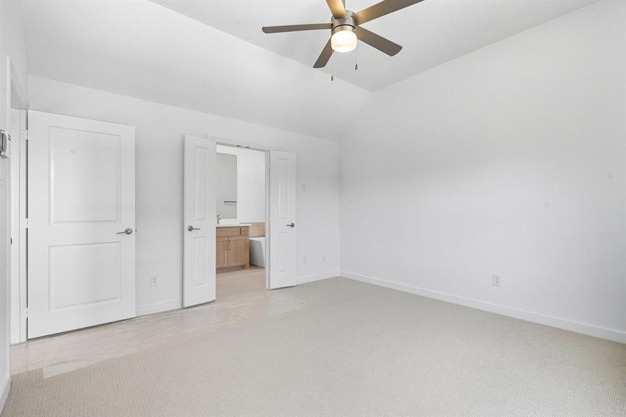 Unfurnished bedroom featuring light carpet, ensuite bathroom, lofted ceiling, and ceiling fan Unfurnished bedroom featuring light carpet, ensuite bathroom, lofted ceiling, and ceiling fan