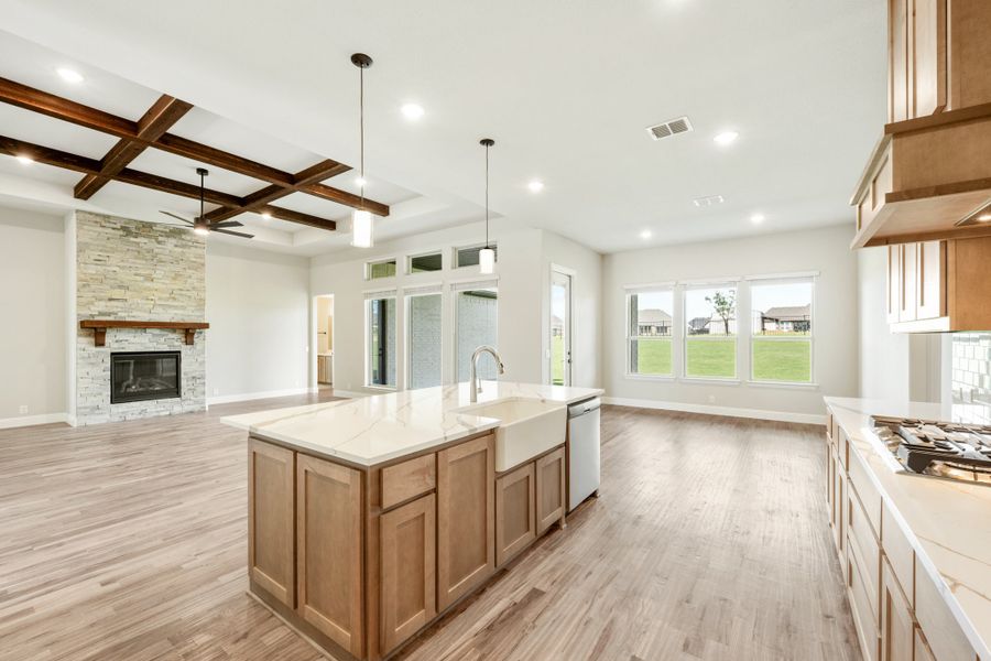 Open kitchen with large island, farmhouse sink, wood beams, and stone fireplace in adjoining living area Open kitchen with large island, farmhouse sink, wood beams, and stone fireplace in adjoining living area