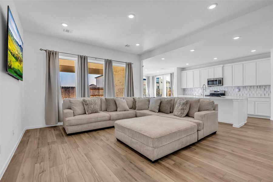 Main Living Area: An expansive, light-filled gathering space where wide-plank flooring, recessed lighting, and generous scale create an immediate sense of comfort and ease. The open flow into the kitchen and backyard views make this room ideal for everyday living and effortless entertaining. Main Living Area: An expansive, light-filled gathering space where wide-plank flooring, recessed lighting, and generous scale create an immediate sense of comfort and ease. The open flow into the kitchen and backyard views make this room ideal for everyday living and effortless entertaining.