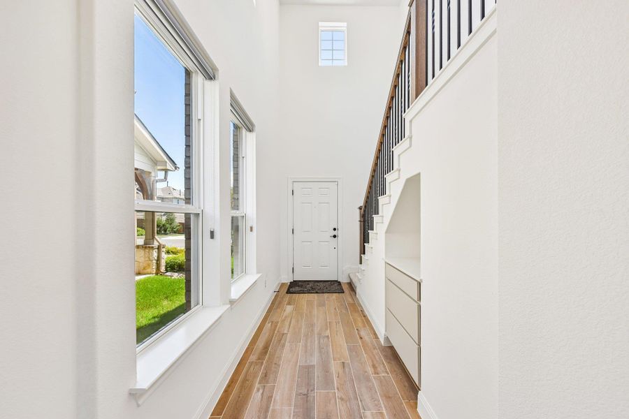 A grand entrance with high ceilings, tall windows, and sleek wood flooring welcomes you home.