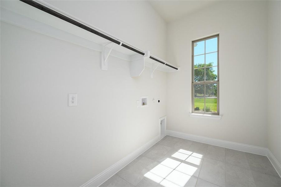 Clothes washing area featuring washer hookup, light tile patterned floors, and electric dryer hookup