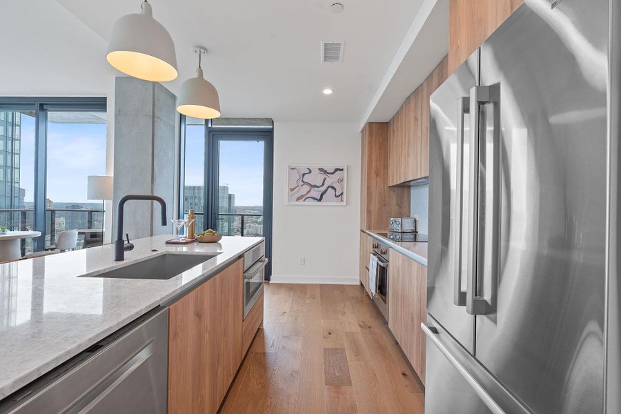 Representative Photo. Kitchen featuring custom Italkraft cabninetry, terrazzo backsplash, waterfall-edge terrazzo countertops, stainless steel Bosch appliances, and pendant lighting above kitchen island