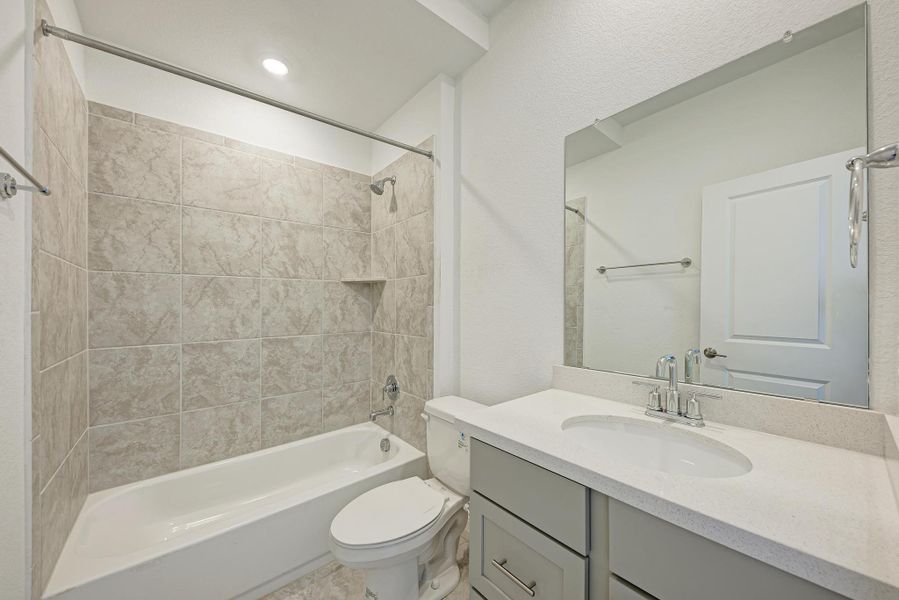 A well-appointed bathroom features a tub-shower combination with tiled walls and a modern vanity with ample counter space.