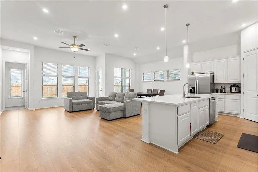 Kitchen with decorative light fixtures, open floor plan, white cabinets, light wood-style flooring, and recessed lighting Kitchen with decorative light fixtures, open floor plan, white cabinets, light wood-style flooring, and recessed lighting