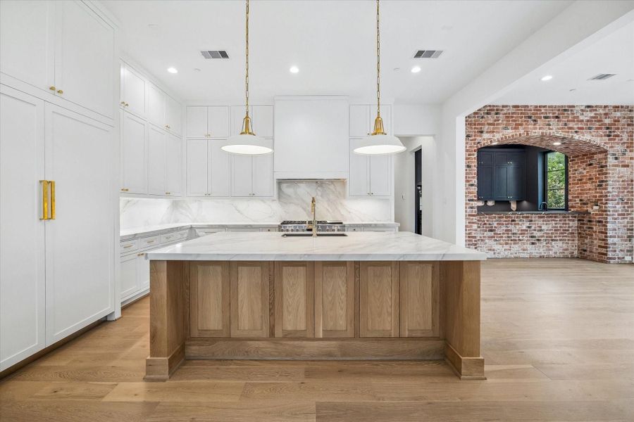 Kitchen and adjacent dining room, with a bar just off the dining area featuring a charming exposed brick arch.