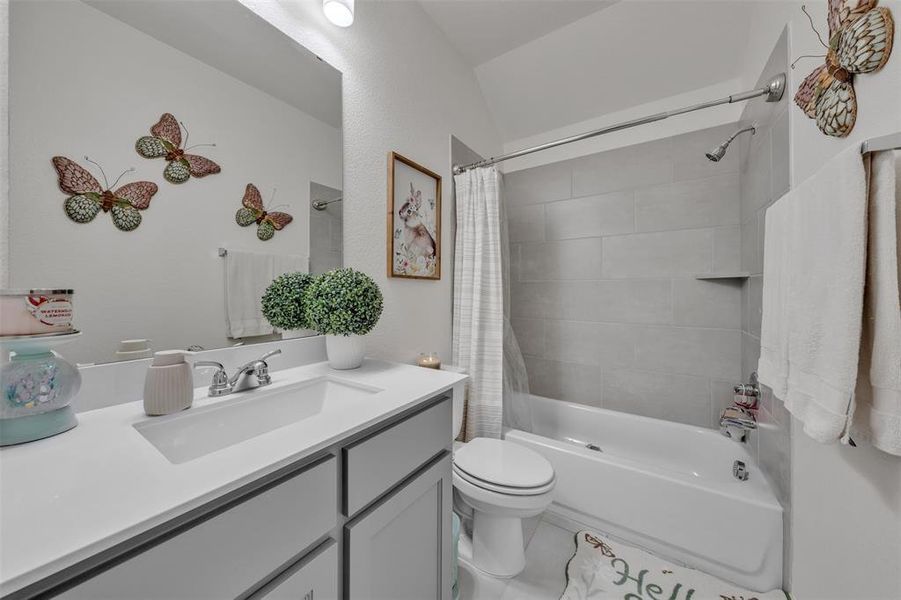 Bathroom featuring a white vanity with an integrated sink, chrome faucet, and gray cabinetry Bathroom featuring a white vanity with an integrated sink, chrome faucet, and gray cabinetry