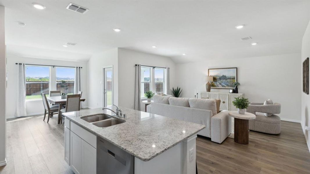 Kitchen featuring white cabinets, open floor plan, light stone countertops, light wood-type flooring, and stainless steel dishwasher
