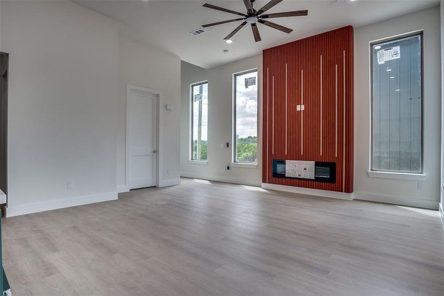 Unfurnished living room featuring ceiling fan and light wood-type flooring Unfurnished living room featuring ceiling fan and light wood-type flooring