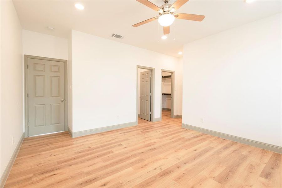 Unfurnished bedroom with a walk in closet, ceiling fan, recessed lighting, and light wood finished floors