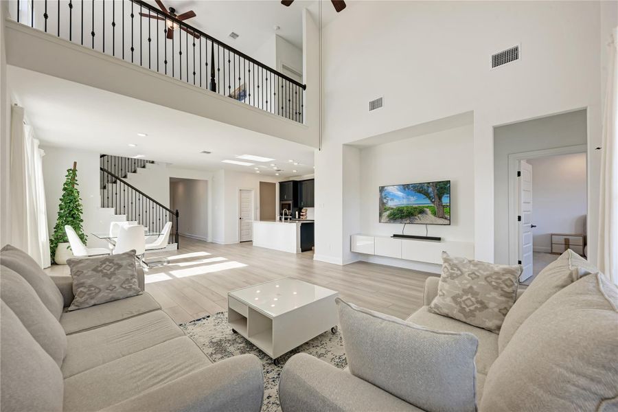 Vaulted living space featuring wood-finish flooring, an open mezzanine, and a contemporary media console