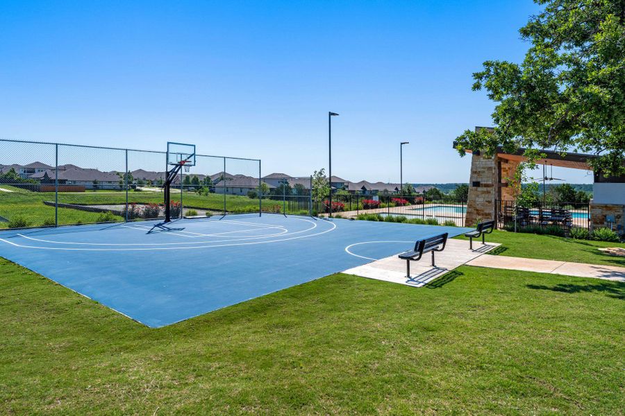 Regulation-size basketball court featuring a blue playing surface and perimeter fencing