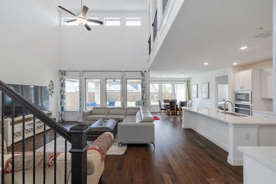 Living room featuring baseboards, a towering ceiling, dark wood-style floors, stairway, and recessed lighting