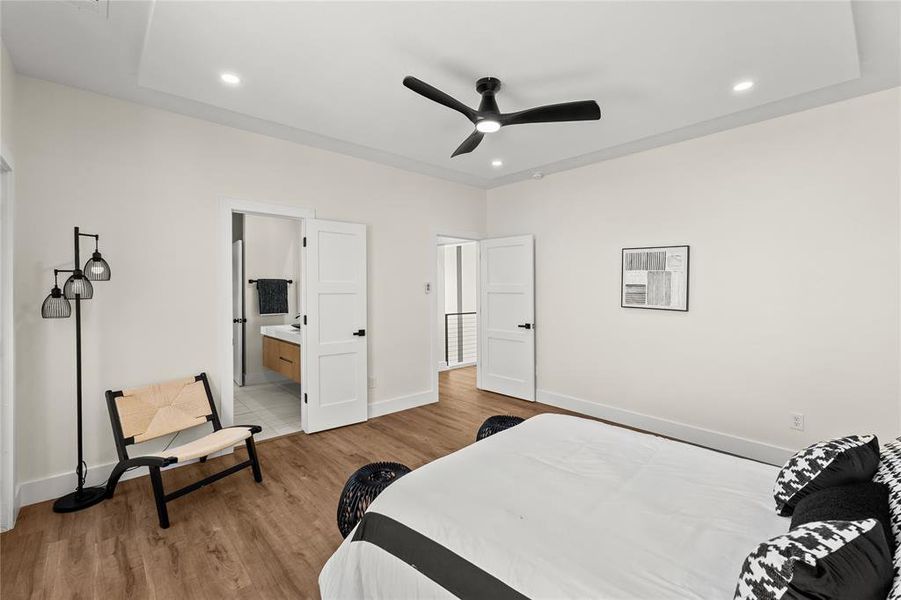 Bedroom with light wood-style flooring, ceiling fan, recessed lighting, and connected bathroom